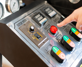 Oil 5 A close-up view of a control panel with various buttons and gauges. A finger is poised to press a large red button labeled ACTIVATION. Other buttons are colored green, or